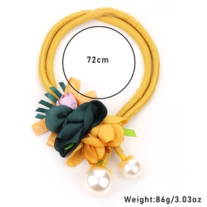 Close-up of fabric flowers and imitation pearls on a yellow braided choker necklace