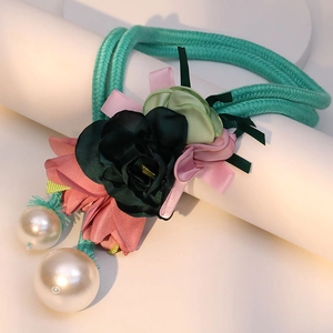 Exaggerated floral fabric necklace with pearls on a white display stand for women