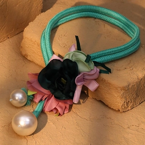 Detailed shot of teal braided necklace with fabric flowers and large faux pearls