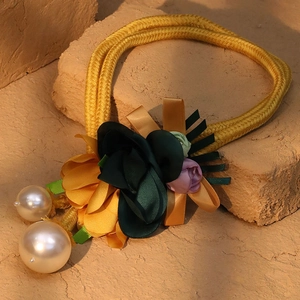 Detail of fabric flowers and faux pearls on a golden woven cord for kimono decoration
