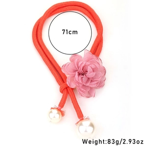 Detail view of woven orange rope necklace with pink chiffon flower and pearl charms