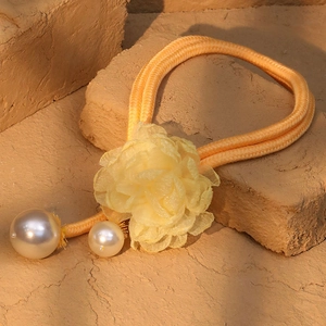 Detailed view of yellow mesh flower necklace with dual braided cords and faux pearl charms