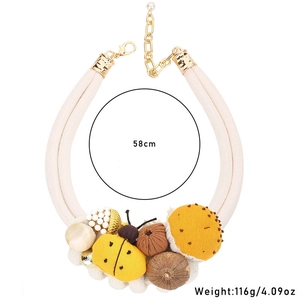 Detail view of woven rope necklace showing ladybug and mushroom charms with 58cm length