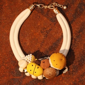 Handmade forest style necklace with insect mushroom pendants on rustic stone background
