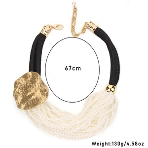 Macro detail of layered pearl necklace with large hammered gold alloy pendant and 67cm length