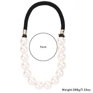 Macro view of a 74cm long oversized white faux pearl necklace with black braided cord