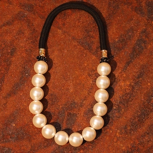 Elegant white pearl choker necklace with black cord and textured gold hardware detail