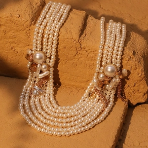 Elegante mehrlagige Perlenkette mit goldenen Vintage-Akzenten auf strukturiertem Stein