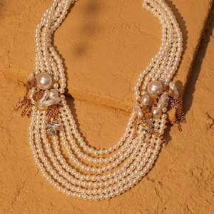 Elegante mehrlagige Perlenhalskette mit goldenen Akzenten auf einem steinernen Hintergrund