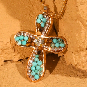 Cross pendant necklace with sparkling rhinestones and blue beads on a warm rocky backdrop