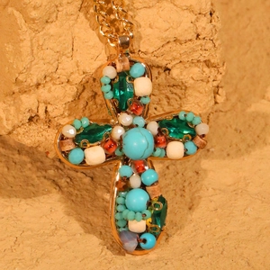 Collier pendentif croix dorée fait main avec perles colorées sur fond de pierre