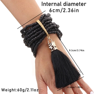 Detail eines mehrlagigen Perlenarmbands mit langen schwarzen Quasten und goldener Metallstange