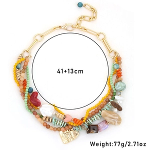 Détail du collier multicouches avec perles en pierre et pendentifs en forme de cœur doré
