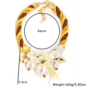 Detail of chunky gold cord necklace with large pearls and golden flower pendant