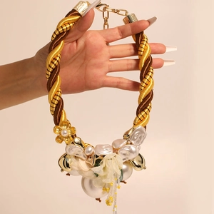 Detail of chunky twisted rope necklace with baroque pearls and gold floral charms