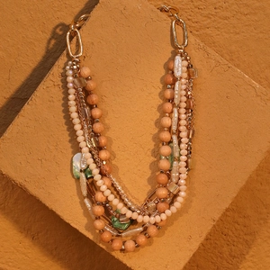 Bohemian multi-layer necklace with wooden beads and green stone pendant on stone backdrop