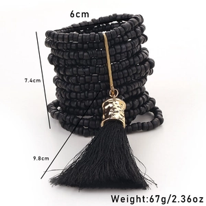 Macro shot of multi-layer black wood bead bracelets with gold hardware and long tassels