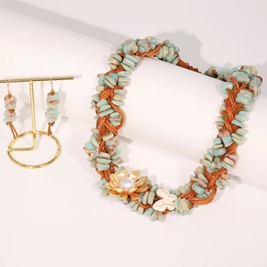 Detalle de collar artesanal de piedra natural tejida con flor dorada y mariposa