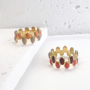 Minimalist enamel wave rings in colorful oval designs on textured stone steps