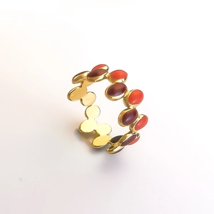 Detailed macro view of gold-plated oval ring with alternating red enamel inlays