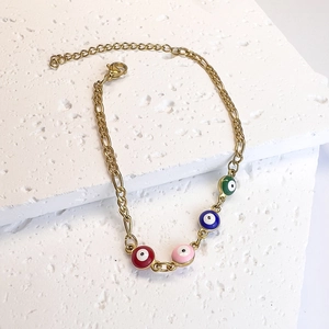 Detail of gold Figaro chain bracelet with colorful evil eye charms and lobster clasp