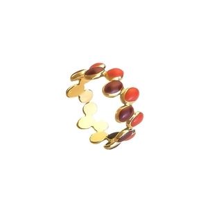 Golden wavy ring with alternating red and maroon oval enamel gems on white background