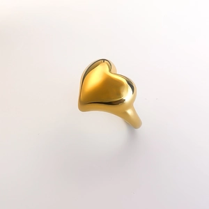 Macro detail of high-polished 18K gold heart-shaped minimalist ring on white background
