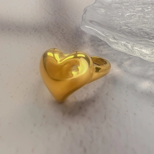Macro detail of wide 18K gold plated heart ring with smooth polished finish and open band