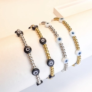 Set of four gold and silver beaded bracelets featuring colorful Evil Eye charms on white stand