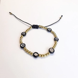Detail of adjustable evil eye bead bracelet with gold accents and black braided cord