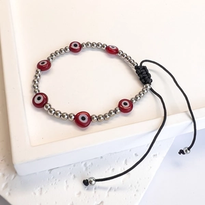 Detail view of woven Turkish evil eye bracelet with red beads and adjustable black cord