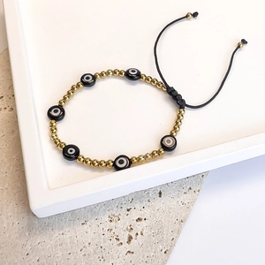 Detail of adjustable evil eye bead bracelet with golden accents on stone base