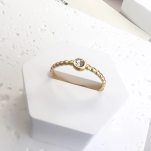 Minimalist gold beaded ring with a sparkling round-cut gemstone bezel setting