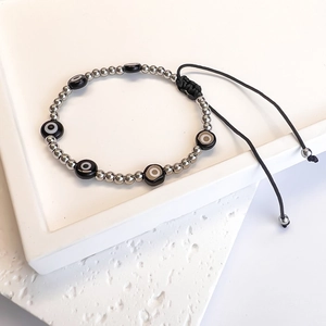 Detail of hand-woven evil eye bead bracelet with silver beads on a textured white stone