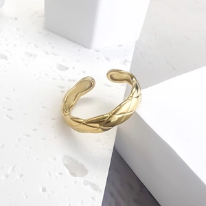 Golden quilted pattern stainless steel ring on minimalist geometric stone stand