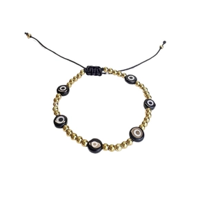 Handmade woven evil eye bracelet with gold beads and black glass talismans on white background