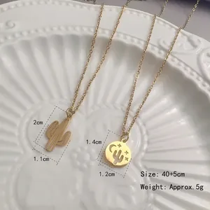 Collier en acier inoxydable doré avec pendentif cactus et lune sur fond céramique blanc