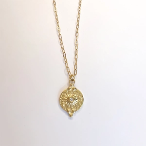 Détail d'un collier plaqué or avec pendentif soleil et centre en zircon transparent