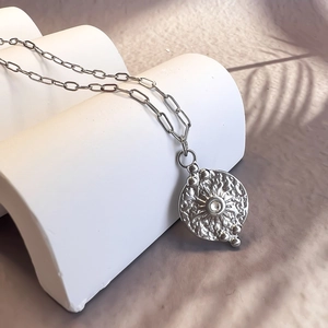 Détail du collier médaillon argenté avec texture rayonnante et oxyde de zirconium