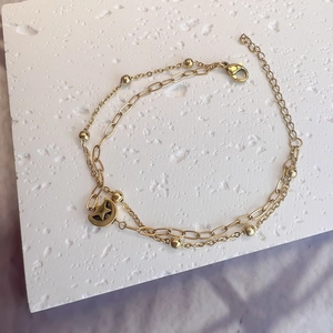 Close-up of double-layered gold bracelet with moon star pendant and lobster clasp