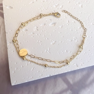 Detail of double-layer stainless steel bracelet with round pendant and bead chain