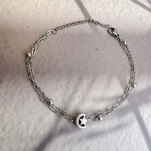 Detail of silver double-layered stainless steel chain with hollow moon and star pendant