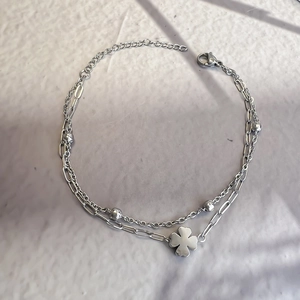 Detail view of double-layer stainless steel bracelet featuring a four-leaf clover charm