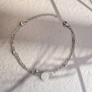 Detail view of double-layered stainless steel chain bracelet with round charm and beads