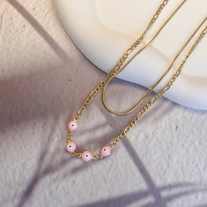 Close-up of double-layer gold snake chain with pink enamel evil eye beads detail