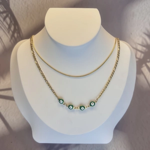 Double-layered 18K gold plated stainless steel necklace featuring green evil eye charms
