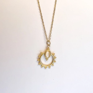 Close-up of golden sunburst pendant with cat eye stone on a vintage stainless steel necklace