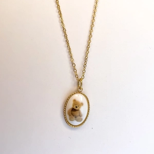 Detailed macro view of 18K gold teddy bear oval pendant with micro-bead edges
