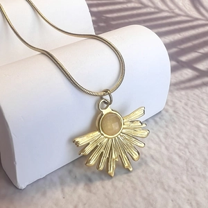 Detail of gold fan pendant with yellow natural stone on a sleek snake chain necklace