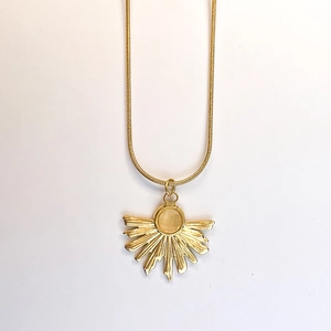 Close-up of gold fan-shaped pendant with round gemstone on a sleek snake chain